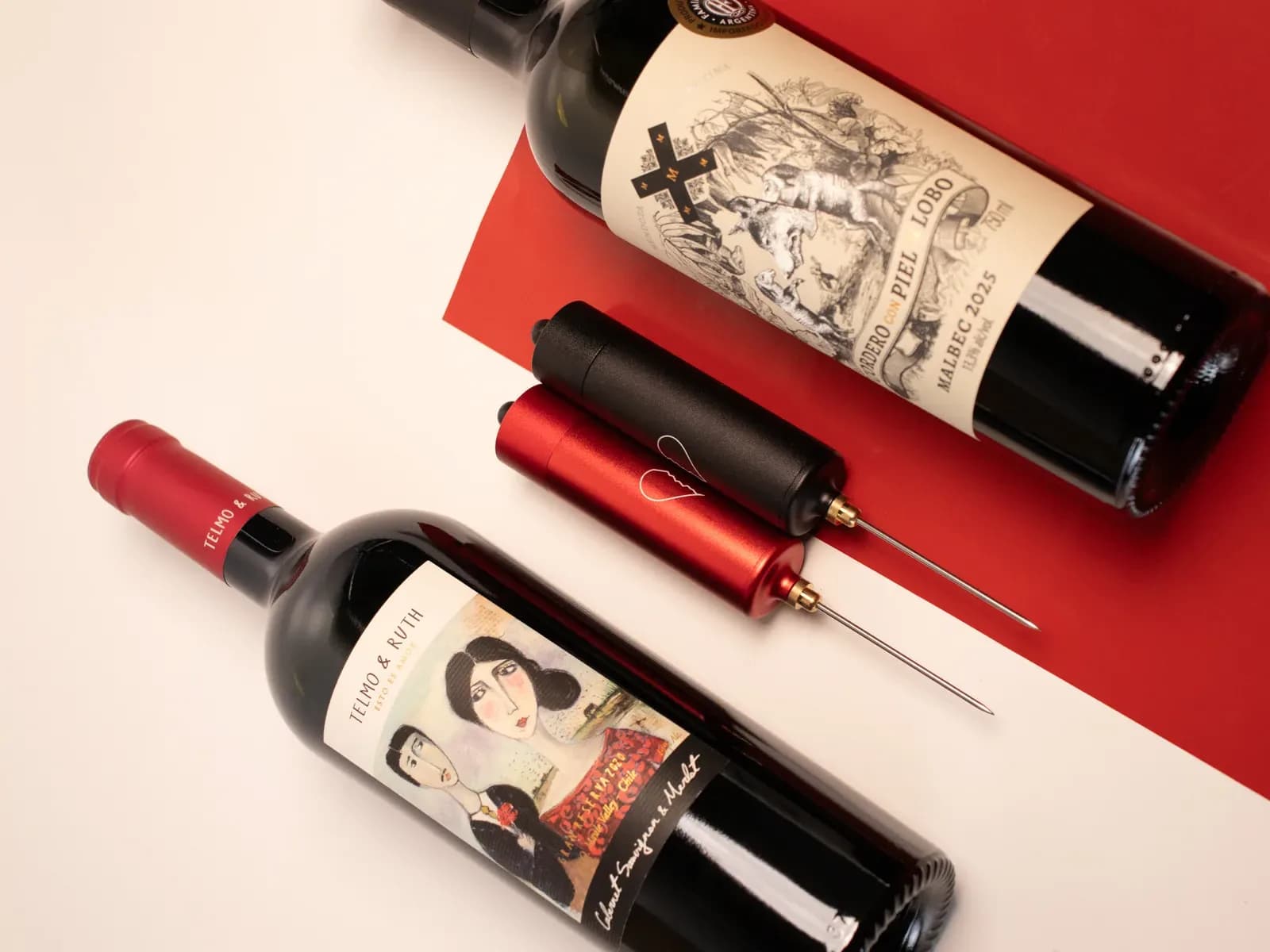 Winepopper Clássico vermelho e preto com gravação, entre duas garrafas de vinho — presente